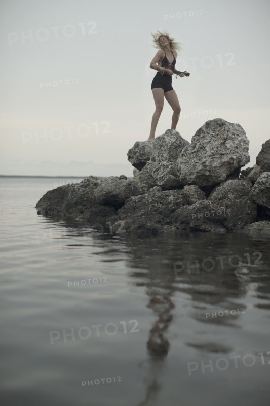 Caucasian woman standing on rocks by remote lake
