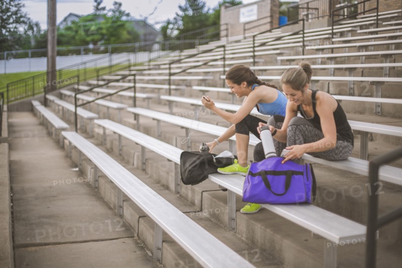 Women packing gym bags on bleachers