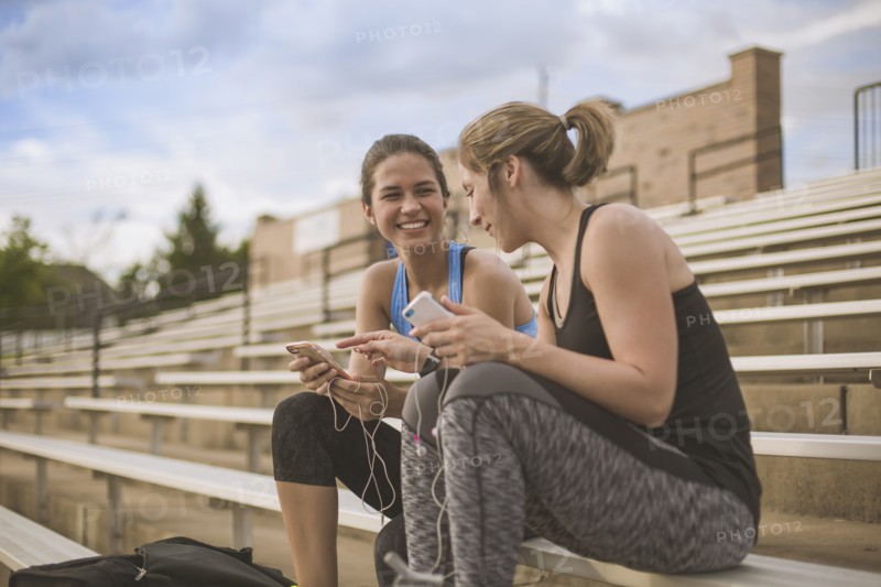 Women using cell phones on bleachers