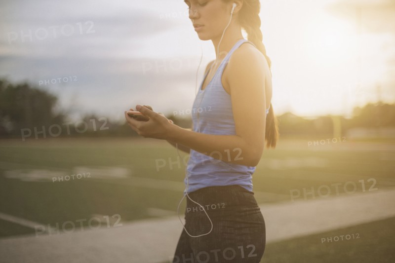 Mixed race athlete listening to mp3 player on sports field