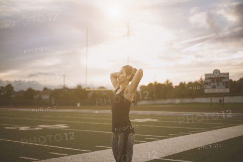 Caucasian athlete tying her hair up on sports field