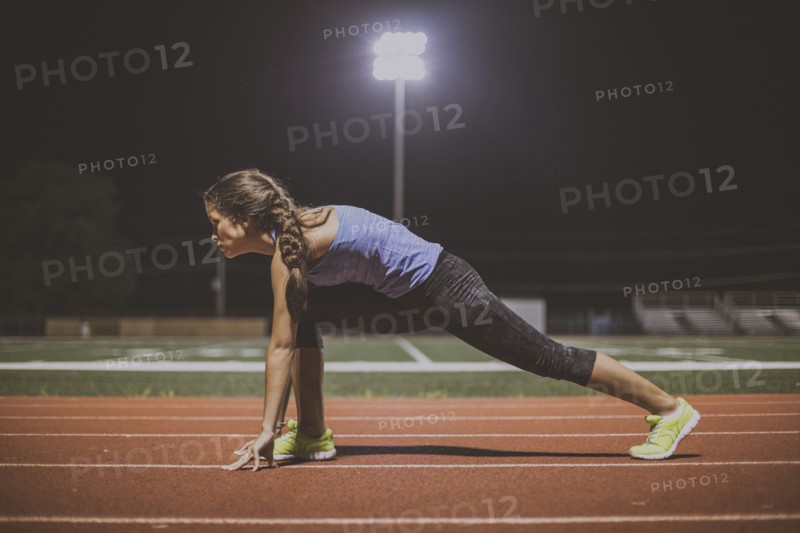 Mixed race runner in starting position on sports field