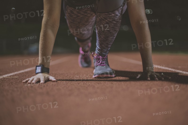 Caucasian runner in starting position on sports field