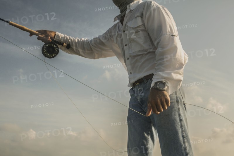 Close up of Caucasian man fishing under blue sky