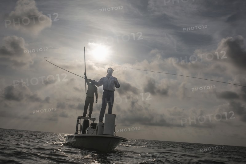Caucasian fishermen casting lines on boat