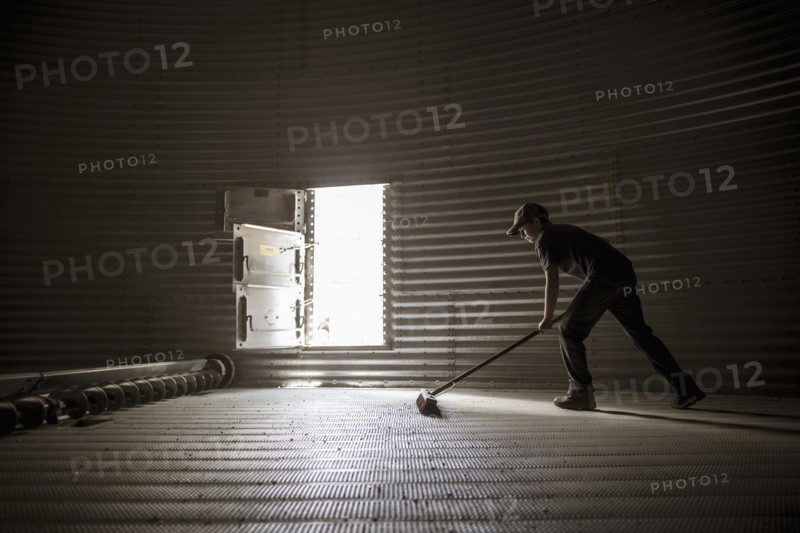 Caucasian boy sweeping empty silo
