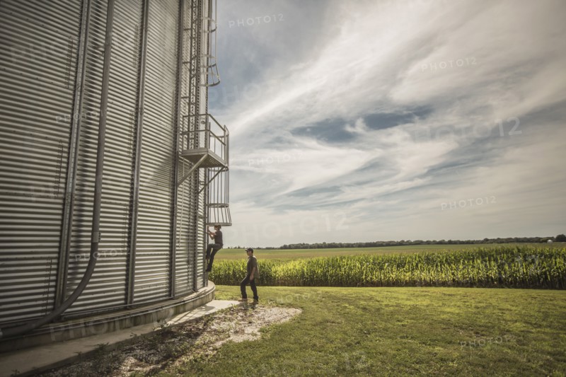Caucasian farmer and son climbing grain silo