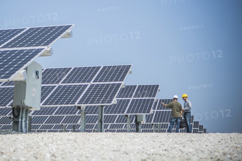 Caucasian technicians talking near solar panels