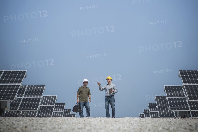 Caucasian technicians talking near solar panels