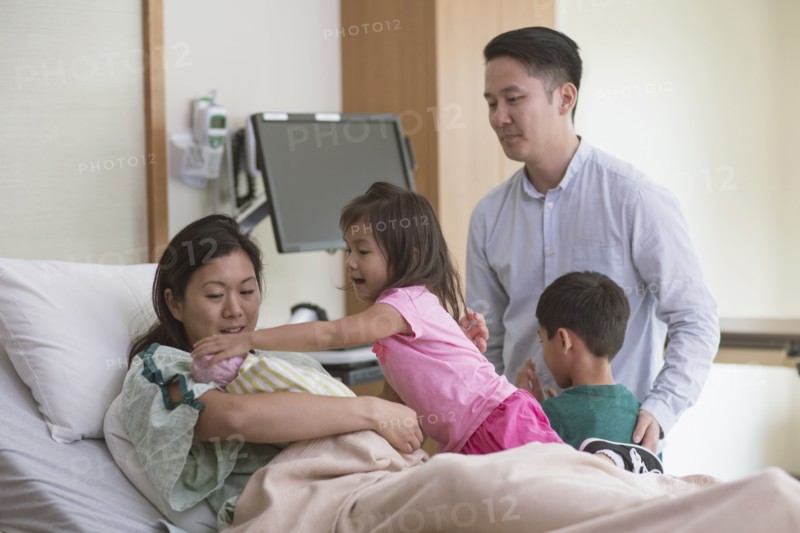 Family admiring newborn baby in hospital room