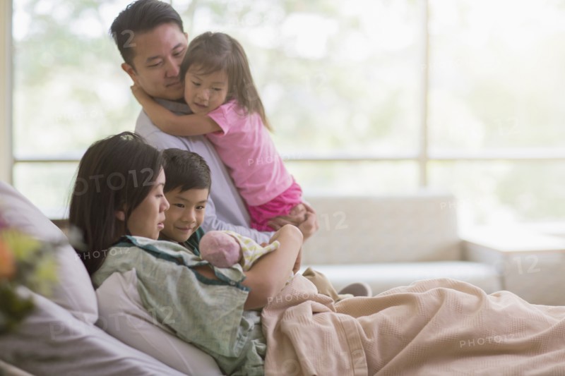 Family admiring newborn baby in hospital room