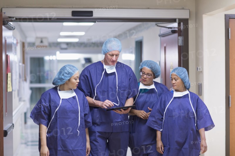 Surgeons using digital tablet in hospital hallway