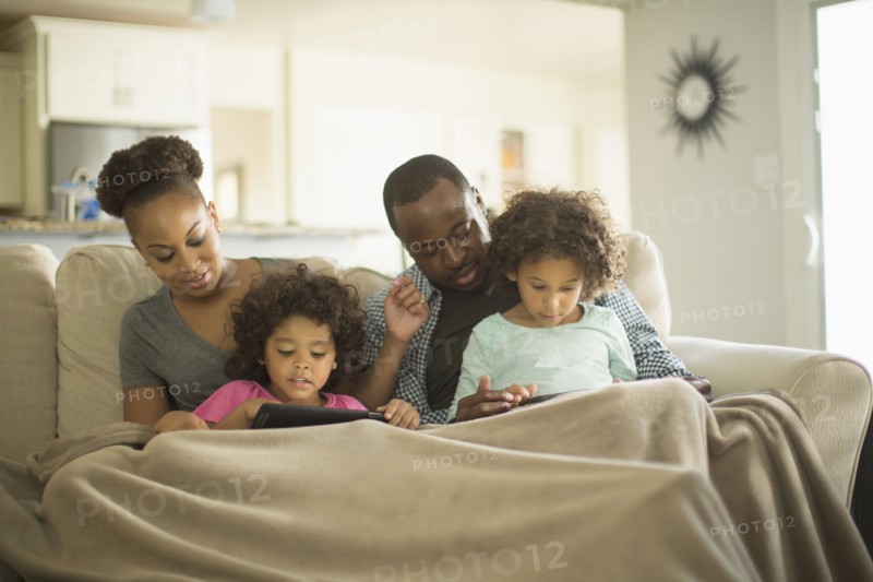 Family using digital tablets on sofa