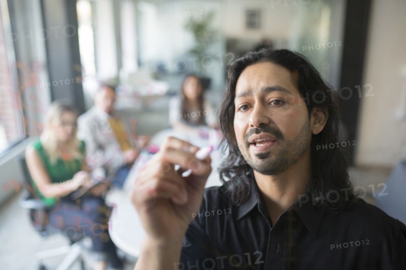 Businessman drawing graph on glass wall in office
