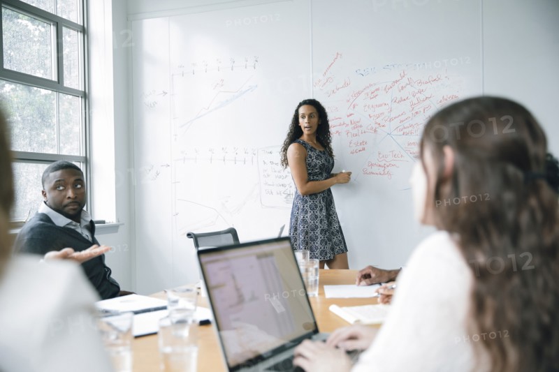 Businesswoman talking at whiteboard in meeting