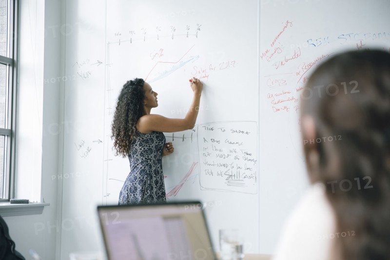 Businesswoman writing on whiteboard in meeting