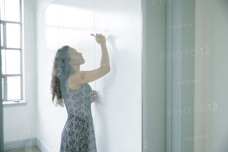 Mixed race businesswoman writing on whiteboard