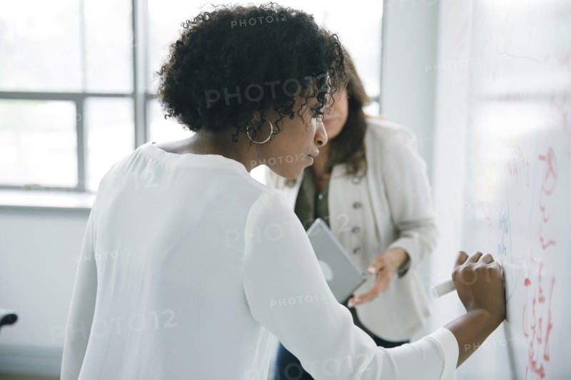 Businesswoman writing on whiteboard in meeting