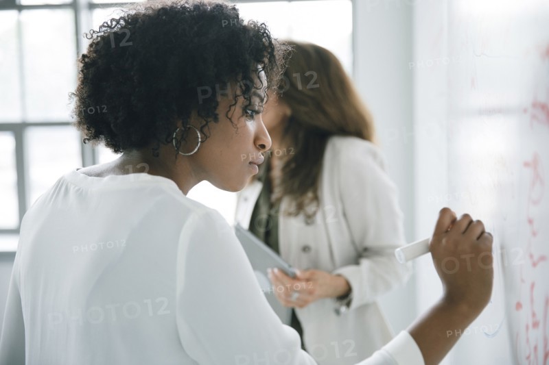Businesswoman writing on whiteboard in meeting