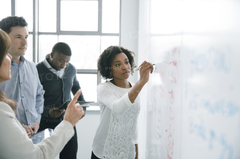 Businesswoman writing on whiteboard in meeting