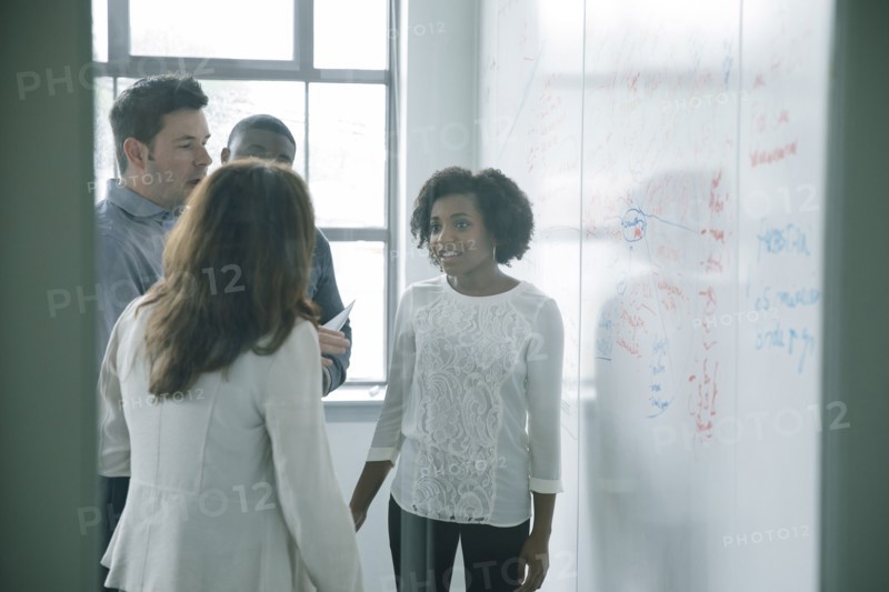 Business people talking near whiteboard in meeting
