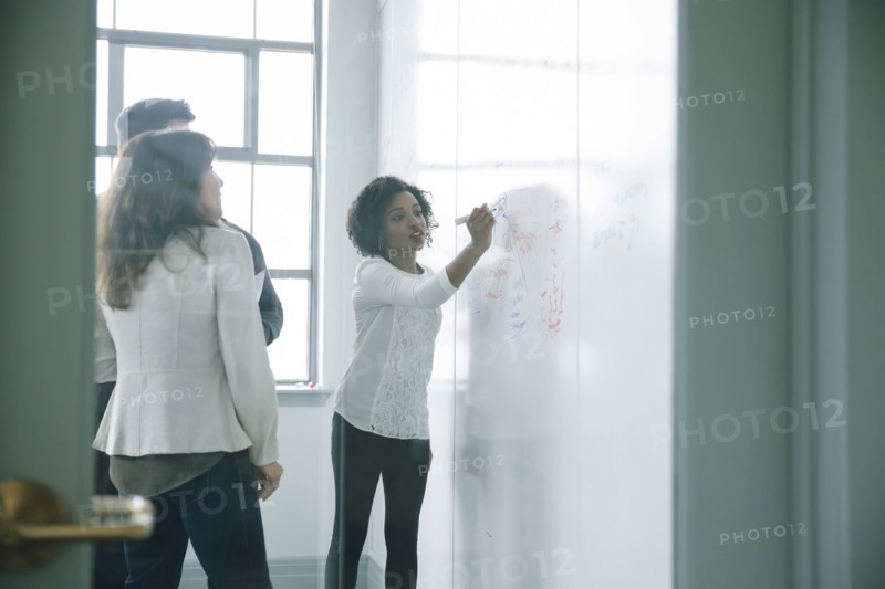 Businesswoman writing on whiteboard in meeting