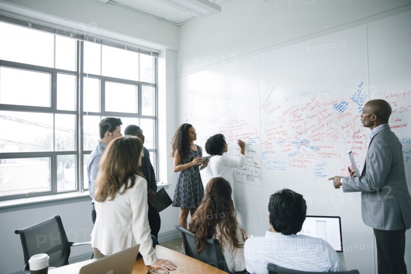 Businesswoman writing on whiteboard in meeting