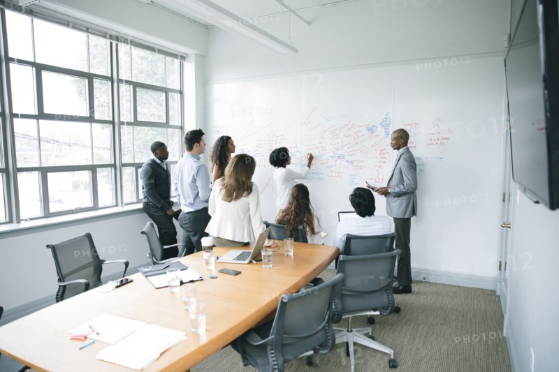 Businesswoman writing on whiteboard in meeting