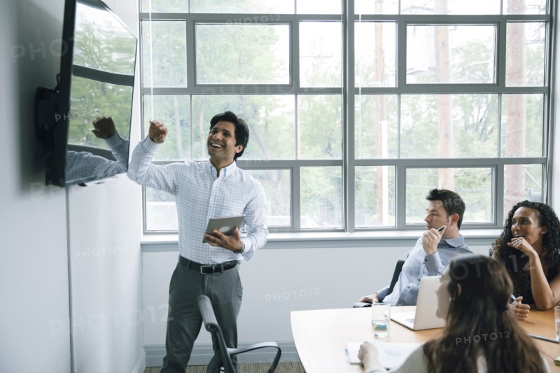 Businessman talking near visual screen in meeting