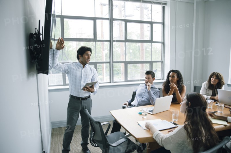 Businessman talking near visual screen in meeting