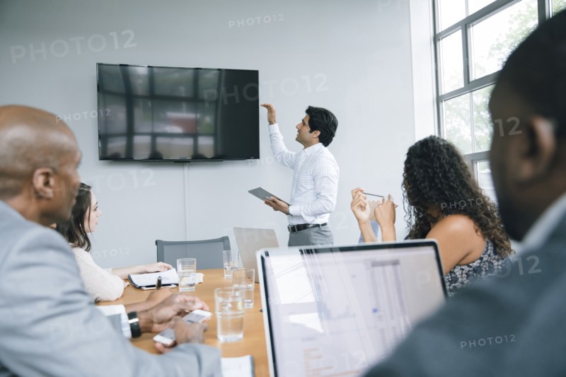 Businessman talking near visual screen in meeting