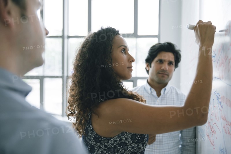 Businesswoman writing on whiteboard in meeting