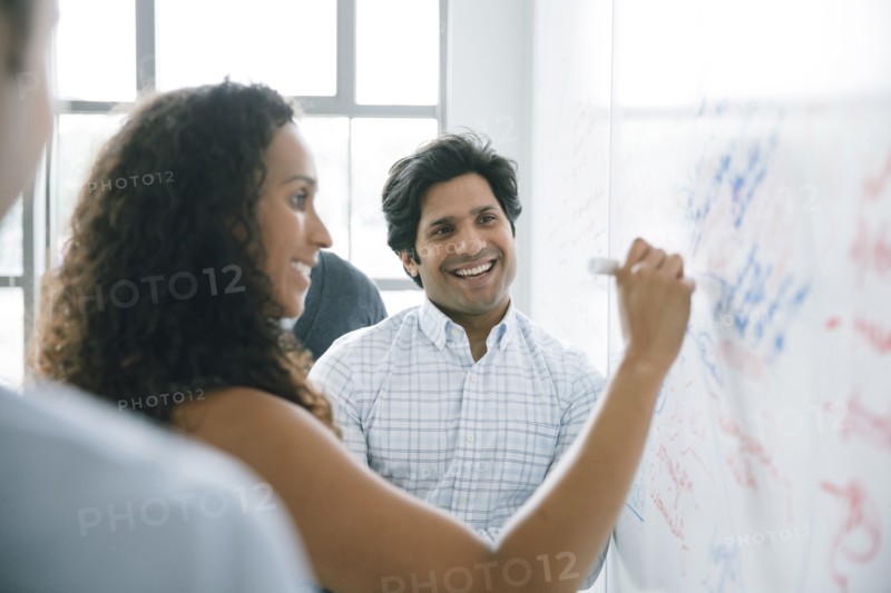 Businesswoman writing on whiteboard in meeting