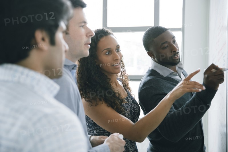 Businessman writing on whiteboard in meeting