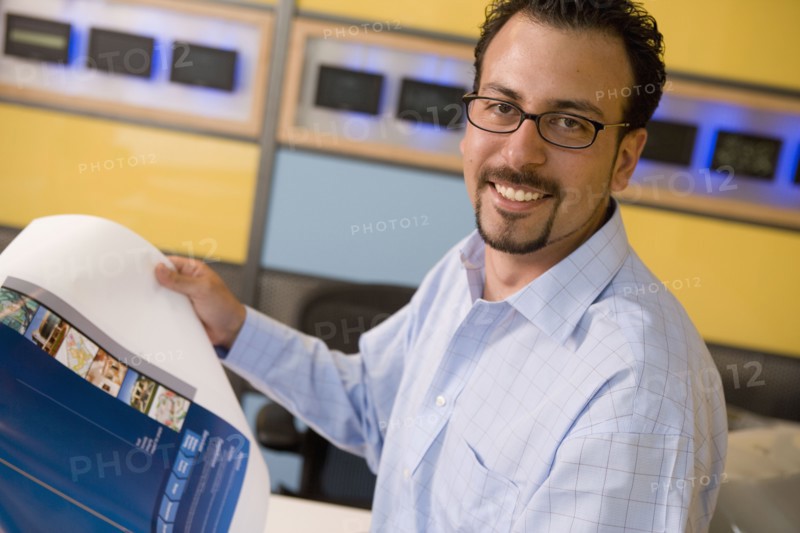 Hispanic male graphic designer holding printout