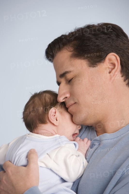 Hispanic father hugging baby