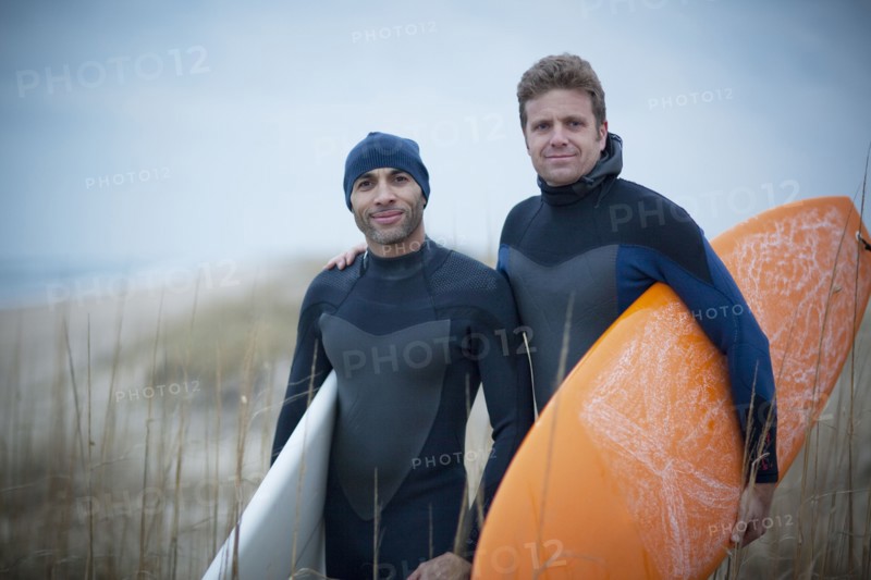 Men wearing wetsuits and carrying surfboards
