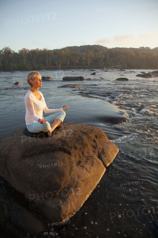 Woman practicing yoga on rock near ocean