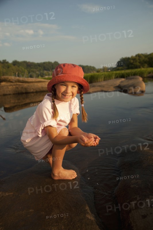African American girl scooping water from river