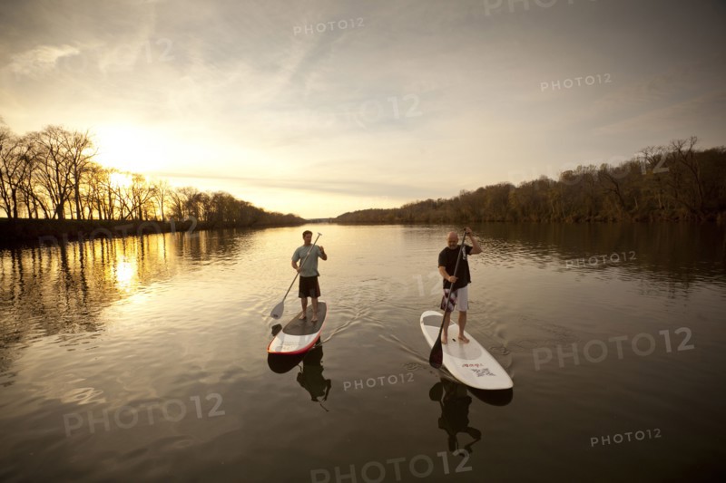 Couple paddling in river on surfboards