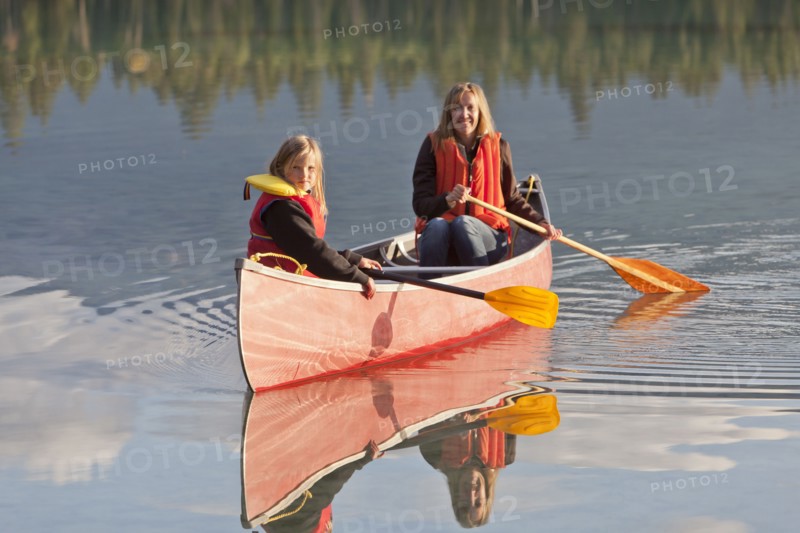 Caucasian mother and daughter canoeing on Lake Edith