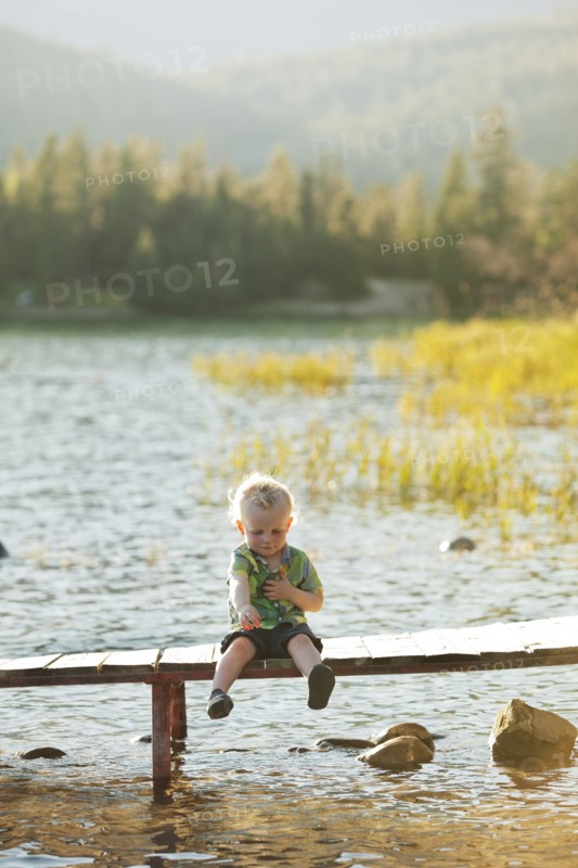 Caucasian boy sitting on wooden deck over lake