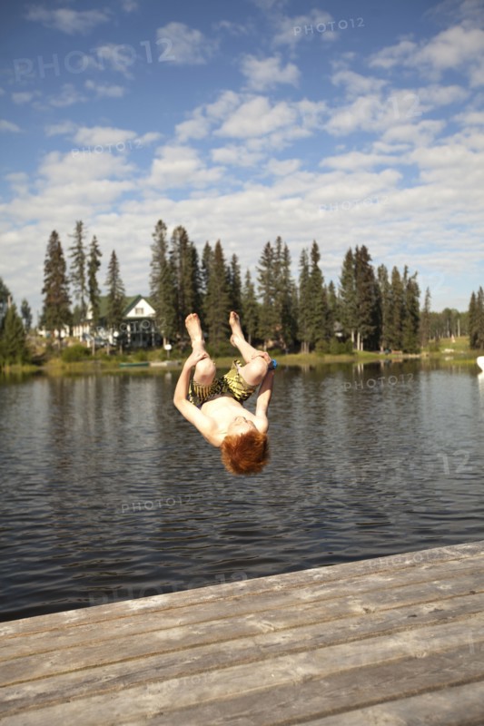 Caucasian boy jumping into lake