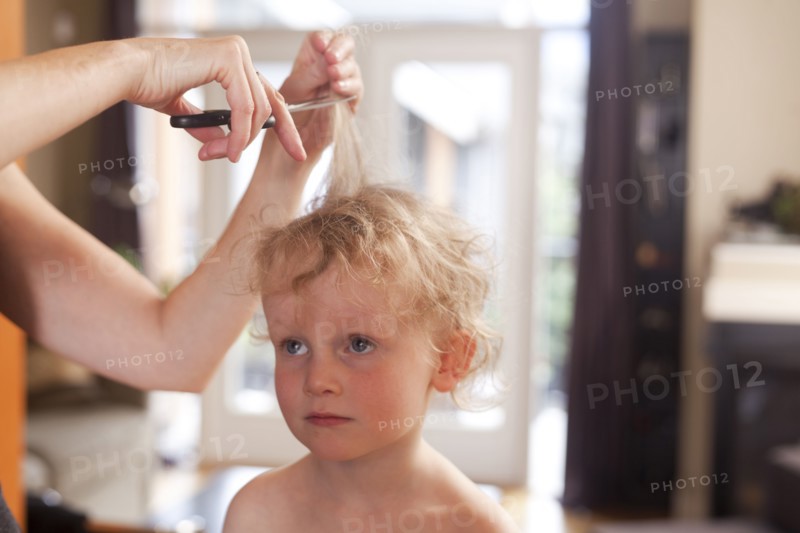 Caucasian mother cutting hair of son