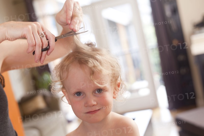 Caucasian mother cutting hair of son