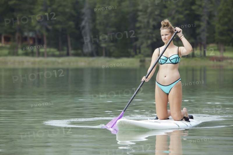 Caucasian girl paddleboarding on lake