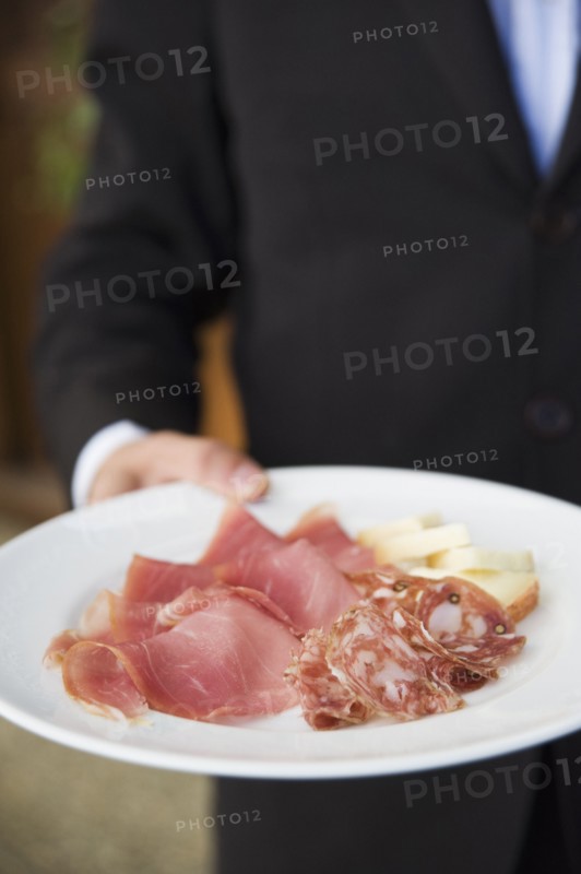 Waiter carrying plate of cured Italian meats