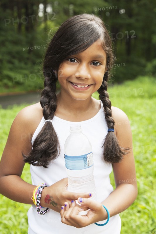 Smiling Hispanic girl holding bottled water
