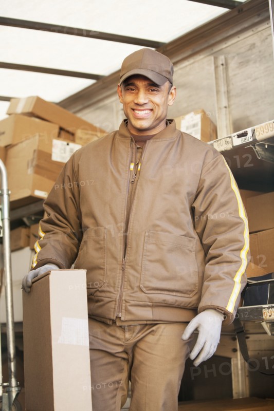 Smiling Hispanic delivery man holding cardboard box