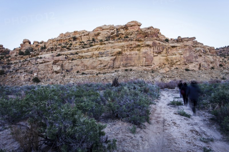 People walking on trail to rock formation